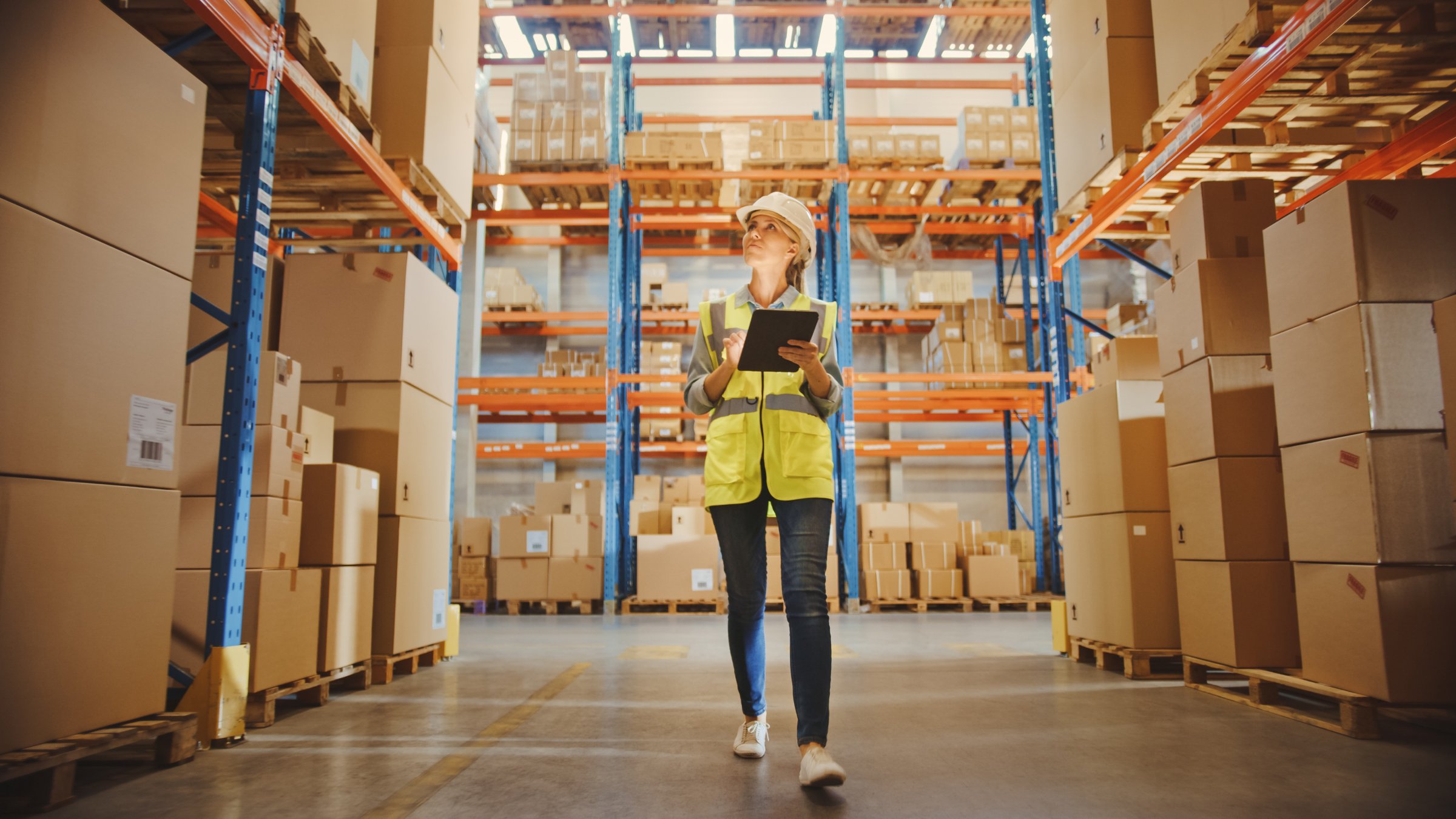 Kvinne som går i lageret og skriver ned tips for lageroptimalisering